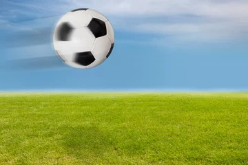 Papier Peint photo Lavable Foot Fliegender Fußball über dem Rasen vor blauem Himmel