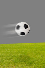 Fliegender Fußball über dem Rasen vor grauem hintergrund