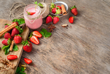 Strawberry smoothies in glass with many strawberries on wooden background. Top view. Copy space