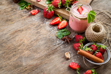Strawberry smoothies in glass with many strawberries on wooden background. Top view. Copy space