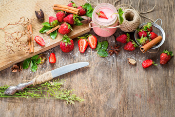 Strawberry smoothies in glass with many strawberries on wooden background. Top view. Copy space