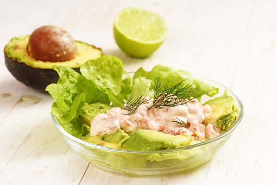 salad from lettuce, crabs in cream and avocado in a glass bowl on a white painted wooden table