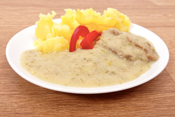 Seitan with dill sauce and potatoes on a table