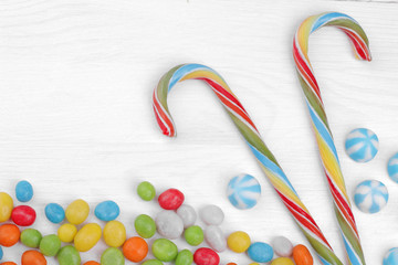 Multicolored round candy and colorful lollipops on a white wooden background. View from above