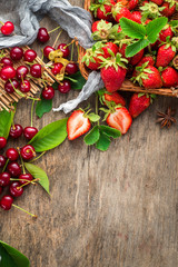 Fresh sweet cherries and strawberries on wooden background. Top view. Copy space. Flatlay