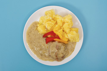 Seitan with dill sauce and potatoes on a blue