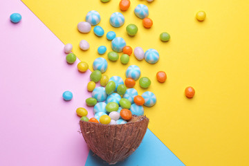 Colorful explosion of sweets in a coconut on bright multi-colored backgrounds, creative still life, top view