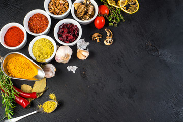 Different spices with raw and dry vegetables on black background. Top view. free space