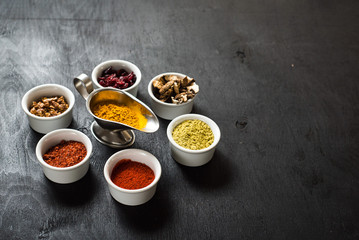 Different spices with raw and dry vegetables on black background. Top view. free space