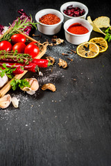 Different spices with raw and dry vegetables on black background. Top view. copy space