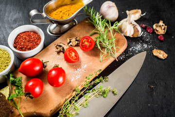 Different spices with raw and dry vegetables on black background. Top view. copy space
