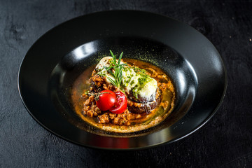 Beet dish with sauce and cheese on black