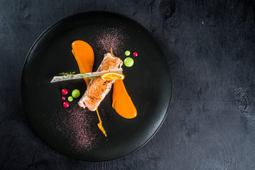 Grilled piece of salmon fish with sauce on black plate - Powered by Adobe