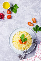 Couscous in a bowl on concrete background. Top view, space for text.