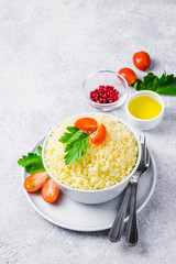 Couscous in a bowl on concrete background. Selective focus, space for text.