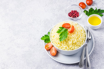 Couscous in a bowl on concrete background. Selective focus, space for text.