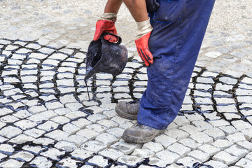 Worker using tar bucket and pouring bitumen into the joints