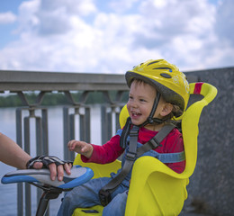 Obraz premium Cute smiling baby boy with safety helmet sitting on the bicycle