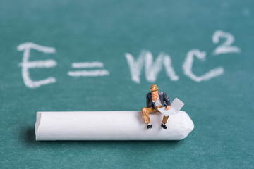 miniature people sitting on chalk stick with the relativity theory background