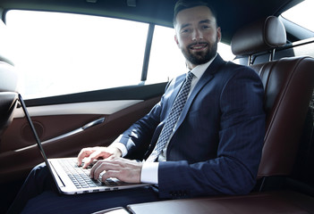 young businesswoman working on her laptop while sitting in the car