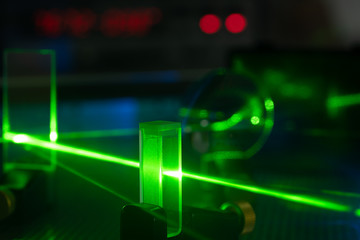 Green laser on optical table in a quantum optics lab. - obrazy, fototapety, plakaty