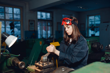 Young woman student works on an automatic lathe CNC, industrial workshop. Concept vocational education turner.