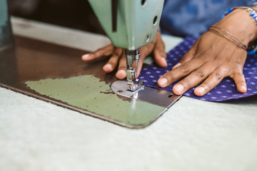 Closeup of a seamstress stitching textiles using her sewing machine