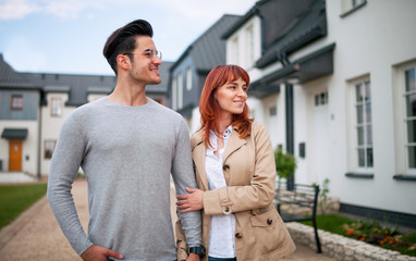 Smiling couple walking at residential area near their new home, real estate concept