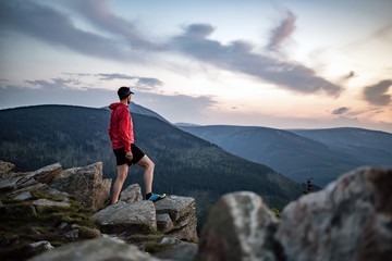 Obraz premium Man celebrating sunset looking at view in mountains