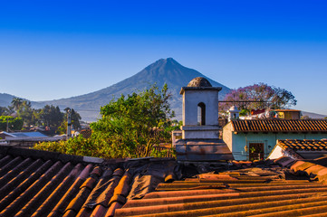 Beautiful outdoor view of rooftops of the building in Antigua city with agua volcano mountain...