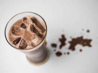 Top view iced chocolate or cacao in clear glass on white isolated background in side view with copy space. Concept to present bitter sweet and delicious drink.