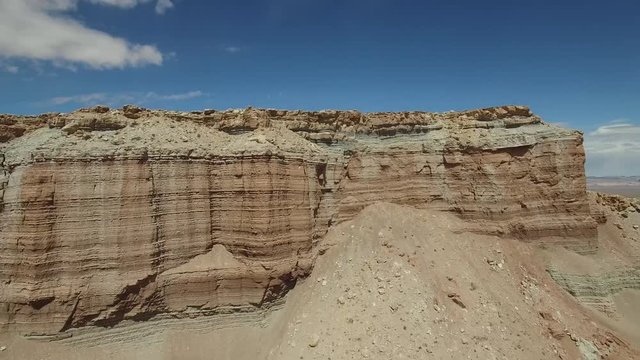 Aerial drone footage of butte and monument in Utah desert landscape  (pulling back)