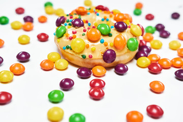 Appetizing golden donut sprinkled with colorful chocolate pellets.