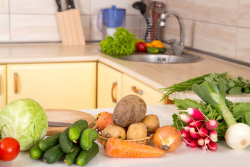 Fresh seasonal vegetables for salad or other vegetable dishes on the kitchen table. Cabbage, tomato, cucumber, onions, radish, beets, carrots - vegetarian food.