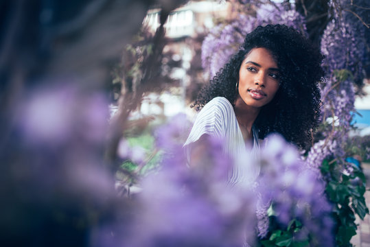 Young black woman sitting surrounded by flowers
