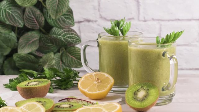 Glasses of green vegetable smoothie. Green vegetable smoothie and ingredients: Kiwi, lemon and herbs.