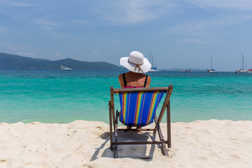 A girl in a white hat sunbathing in a deckchair and looking into