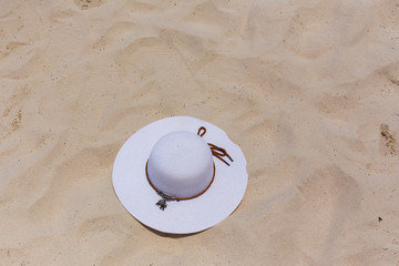 Fototapeta na wymiar A white female hat lies on the sand on the seashore.