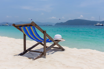 The white hat lies on the edge of the chaise longue, the seashore with a beautiful view.