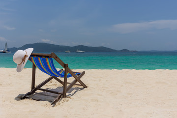 The white hat lies on the edge of the chaise longue, the seashore with a beautiful view.