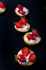  Fluffy buttermilk biscuits shortcake with red ripe strawberries and fresh whipped cream on a black background