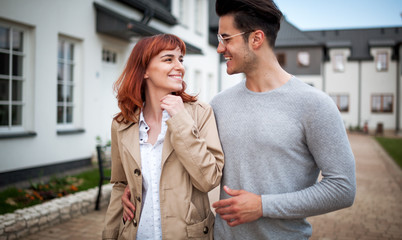 Happy couple walking at residential area in front of their new home