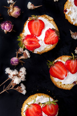 Fluffy buttermilk biscuits shortcake with red ripe strawberries and fresh whipped cream on a black background
