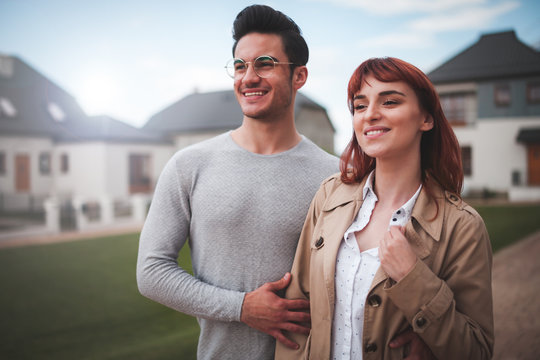Happy couple walking at residential area in front of their new home