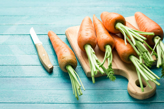 carrots on a blue wooden background, cutting board and knife, fresh vegetables, carotene