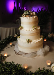 Torta di panna a gradini con decorazioni floreali e candele su sfondo notturno viola