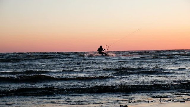 Silhouette of kitesurfer at sea at sunset in summer close up, slow motion