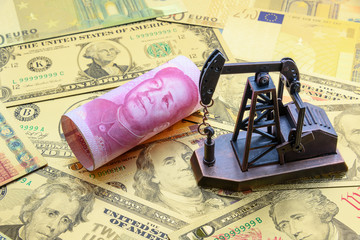 Petroleum, petrodollar and crude oil concept : Pump jack and China CNY yuan on US USD dollar notes, depicts the money received or earned from sales after investment in the development of oil industry.