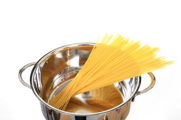 Makaron spagetti , długie nitki w błyszczącym stalowym garnku, przed gotowaniem.