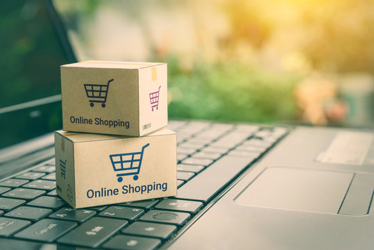 Online shopping / ecommerce and delivery service concept : Paper cartons with a shopping cart or trolley logo on a laptop keyboard, depicts customers order things from retailer sites via the internet.